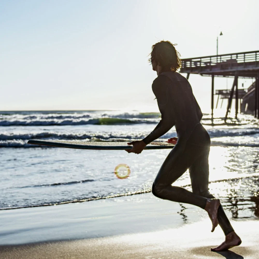 Skimboarder am Strand mit Skimboard in der Hand